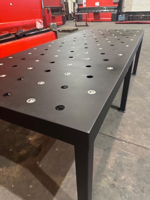 Custom Transfer Table Black metal table with numerous holes on the surface, placed in a workshop.